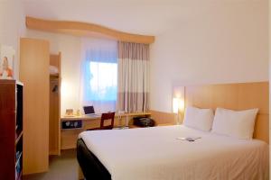 科托努科托努宜必思酒店的酒店客房设有一张大床和一张书桌。