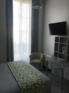 凯恩Smart Appart Caen République的一间卧室配有一张床、一把椅子和电视
