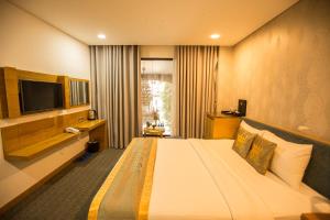 胡志明市The Blue Airport Hotel的酒店客房设有一张大床和一台电视。