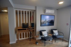 马达莱纳Porto Velho Boutique Hostel的一间房间,配有两把椅子和墙上的电视