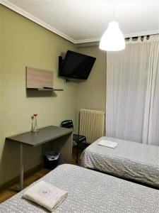 布尔戈斯圣地亚哥旅馆的客房设有两张床和一台墙上的电视。