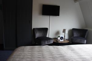 比伦Hotel "De Klok"的酒店客房带两把椅子、一张床和电视。