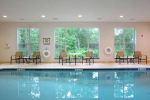 北不伦瑞克北布伦瑞克宿之桥套房酒店的带椅子和桌子的游泳池,位于带窗户的客房内