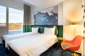 普福尔茨海姆ibis Styles Pforzheim的酒店客房,配有两张床和椅子