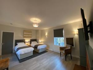 SharnbrookThe Fordham Inn的一间卧室设有两张床、一把椅子和一个窗户。
