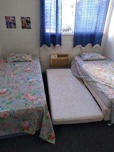 里约热内卢Campo Grande Pousar ou morar的一间卧室设有两张床,窗户配有蓝色窗帘