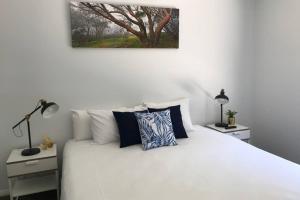 布赖特Mountain Mist Apartments的一间卧室配有一张白色床、两个床头柜和两盏灯。