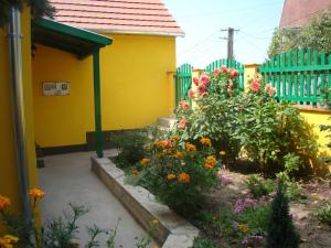 鲍科尼贝尔Sárgarigó Vendégház的黄色房子前面的花园,鲜花盛开