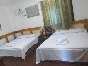 塔比拉兰雷纳纽黑文花园酒店的配有白色床单的客房内的两张床