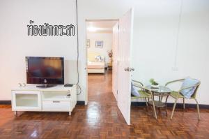 港生Baan Rug Nam Sai的客厅配有电视和桌椅