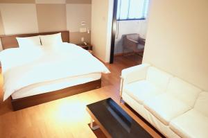 东广岛市LUXe的卧室配有白色的床和沙发