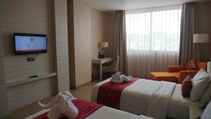 古邦Sotis Hotel Kupang的酒店客房设有两张床和一台平面电视。