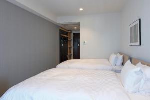 东京Tmark City Hotel Tokyo Omori的配有白色床单的客房内的两张床