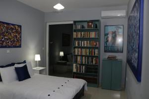 斯巴达Laconian Collection "Lykourgou 10"的一间卧室配有一张床,书架上摆放着书籍