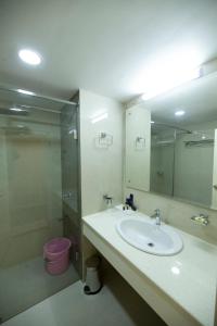 古鲁瓦尤尔Hotel Guruvayur Darshan的一间带水槽、淋浴和卫生间的浴室