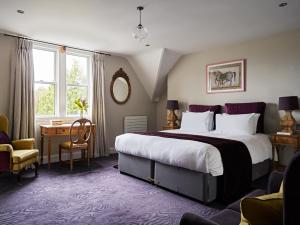 切尔滕纳姆Cotswold Grange的酒店客房设有一张大床和一张书桌。