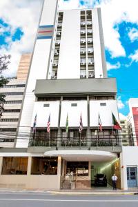 普雷图河畔圣若泽Hotel Dan Inn São José do Rio Preto的前面有旗帜的高大的白色建筑