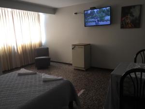 齐克拉约Hotel Plazza的一间设有两张床和一台墙上电视的房间