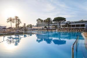 Estepona阿塔拉亚公园玛贝拉酒店的一座拥有蓝色海水和棕榈树的大型游泳池