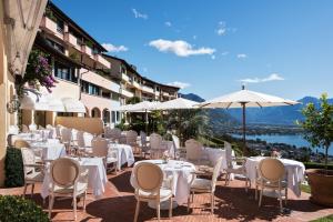 洛迦诺Villa Orselina - Small Luxury Hotel的一间设有白色桌椅和遮阳伞的餐厅