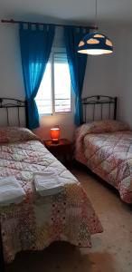 马塔拉斯卡尼亚斯Apartamento Naturaleza Virgen的一间卧室配有两张带蓝色窗帘的床和窗户。