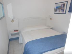 格里莫Luxury apartment in Port Grimaud的卧室配有白色的床和蓝色毯子