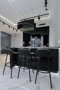 基辅White Tiger Apartment in Smart Plaza的厨房配有黑色凳子和黑色柜台