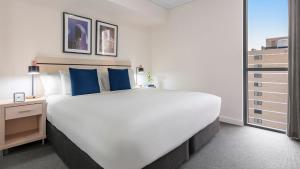 布里斯班Oaks Brisbane Festival Suites的一张大白色的床,里面配有蓝色枕头