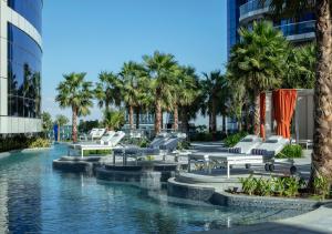 迪拜Paramount Hotel Dubai的一个带躺椅和棕榈树的游泳池