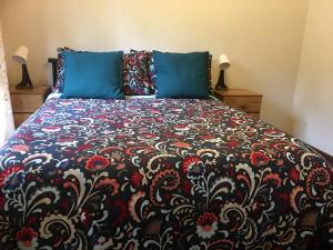 SomersbyFarm guests house的一张带黑色和红色毯子以及蓝色枕头的床