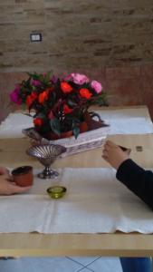 波利卡斯特罗巴森迪诺Appartamenti Centro Policastro的一张桌子,上面有花瓶,上面有一个人拿着纸