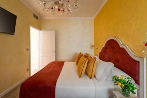 维罗纳帝国旅馆的一间卧室设有一张大床,拥有黄色的墙壁和吊灯。