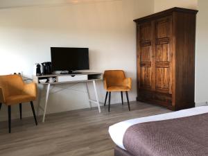 斯希蒙尼克奥赫Strandhotel Om de Noord, logies en ontbijt的一间卧室配有一张桌子、一台电视和两把椅子