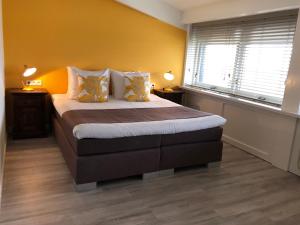 斯希蒙尼克奥赫Strandhotel Om de Noord, logies en ontbijt的一间卧室设有一张黄色墙壁的床和两个窗户