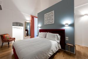 特拉尼I Colori della Puglia Rooms的一间卧室配有一张大床和一把椅子