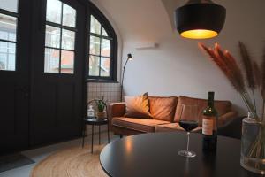 恩斯赫德Overnachten in de oude West-Indiëschool的客厅配有沙发和带葡萄酒玻璃的桌子