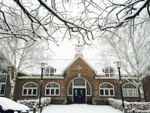 恩斯赫德Overnachten in de oude West-Indiëschool的一座大砖砌的建筑,地面上积雪