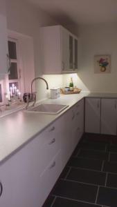 罗斯基勒Hos Anna的厨房配有水槽、白色橱柜和窗户。