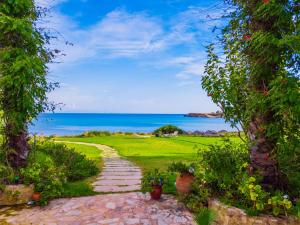 KounopetraKounopetra Beach Luxury Villas的一条穿过花园的小路,花园的背景是大海