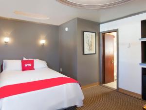 威克斯巴勒OYO Hotel Wilkes-Barre East的卧室配有红色和白色的床和门
