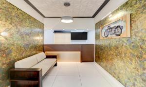 科钦Treebo Trend Petals Suites Ernakulam Town的一间配有沙发的等候室和墙上的绘画