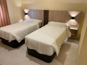 Ontígola帕拉达酒店的配有白色床单的酒店客房内的两张床
