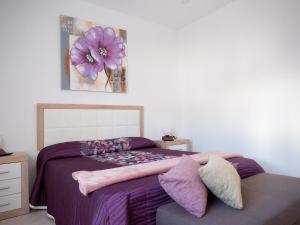 蒂亚斯Casa Bárbara的一间卧室配有一张带紫色床单和花卉绘画的床。