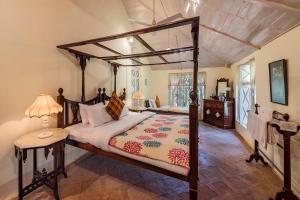 马泰兰SaffronStays Parsi Manor, Matheran的一间卧室配有一张天蓬床和一张带台灯的桌子