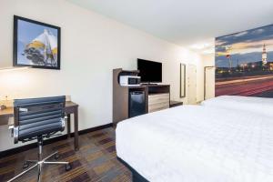 麦迪逊Clarion Pointe Madison-Huntsville的酒店客房设有一张床、一张书桌和一台电视机。