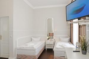 施特拉尔松德施特拉尔松德酒店的客厅配有白色家具和平面电视
