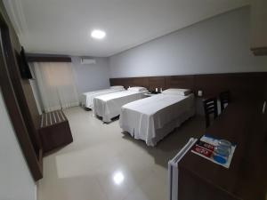 Belo JardimHotel Asa Branca的酒店客房设有三张床和一张桌子
