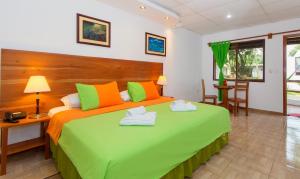 阿约拉港Hotel Twin Galápagos的一间卧室配有一张带橙色和绿色枕头的大床