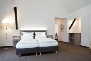 Schledehausen胡内尔宾邮政酒店的卧室配有带白色枕头的大床