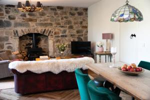克雷盖拉希Dandaleith Cottage No.1的客厅配有桌子和石墙